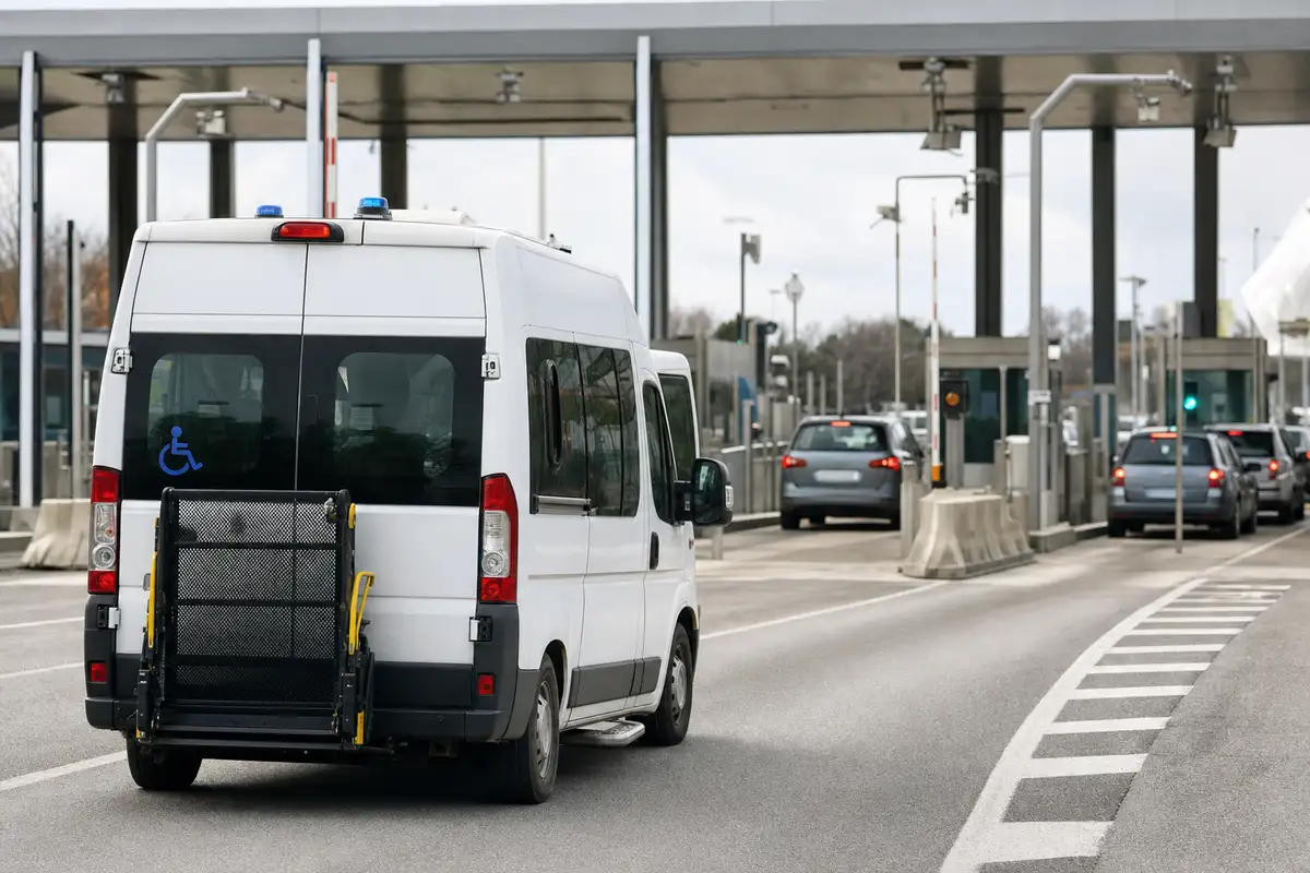 Furgone bianco per trasporto disabili con pedana posteriore al casello autostradale, auto nelle corsie vicine