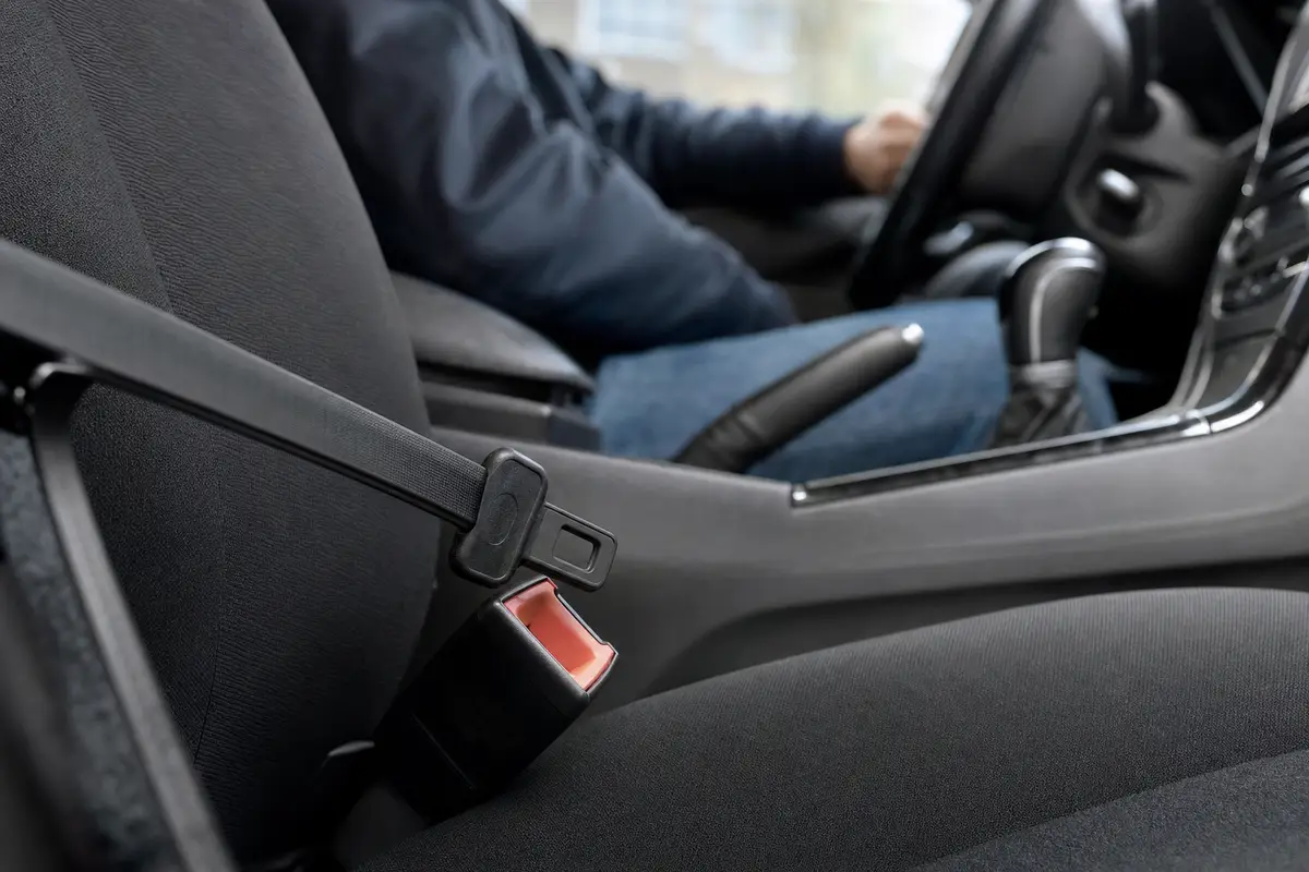Fibbia della cintura in auto con inserto nella chiusura e cintura non indossata, conducente sfocato sullo sfondo