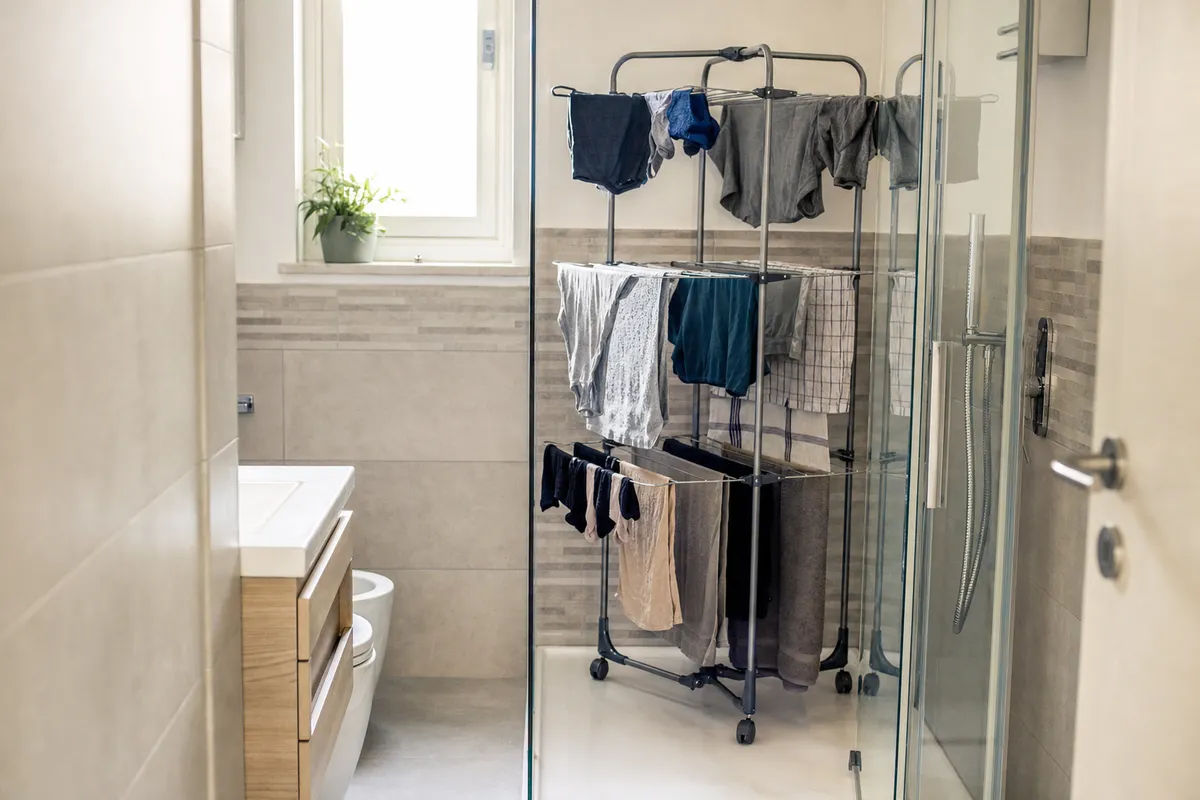 Stendino verticale a torre con bucato appeso dentro un box doccia in un bagno moderno