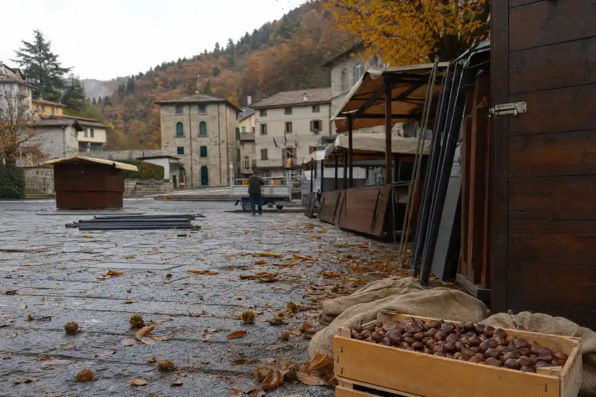 Cassetta di marroni su un telo di iuta in una piazza con bancarelle smontate e foglie d’autunno
